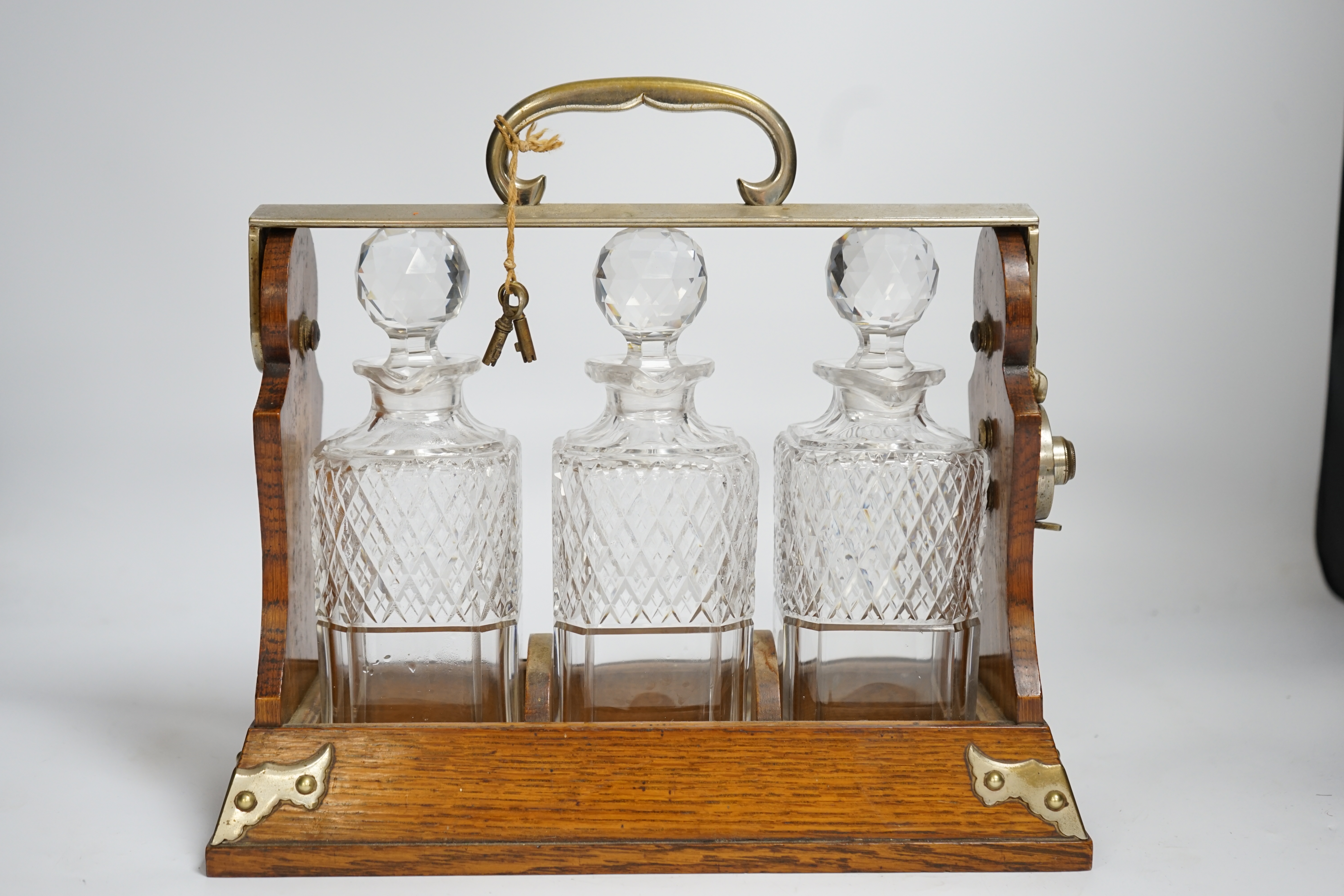 A Betjemann’s patent oak three bottle tantalus with key, 32cm wide